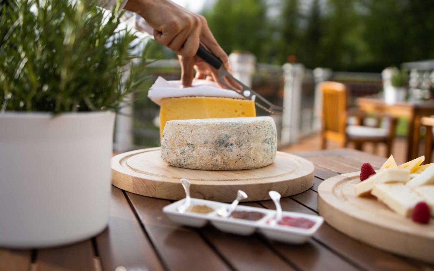 hand holding knife above block of cheese on wooden table